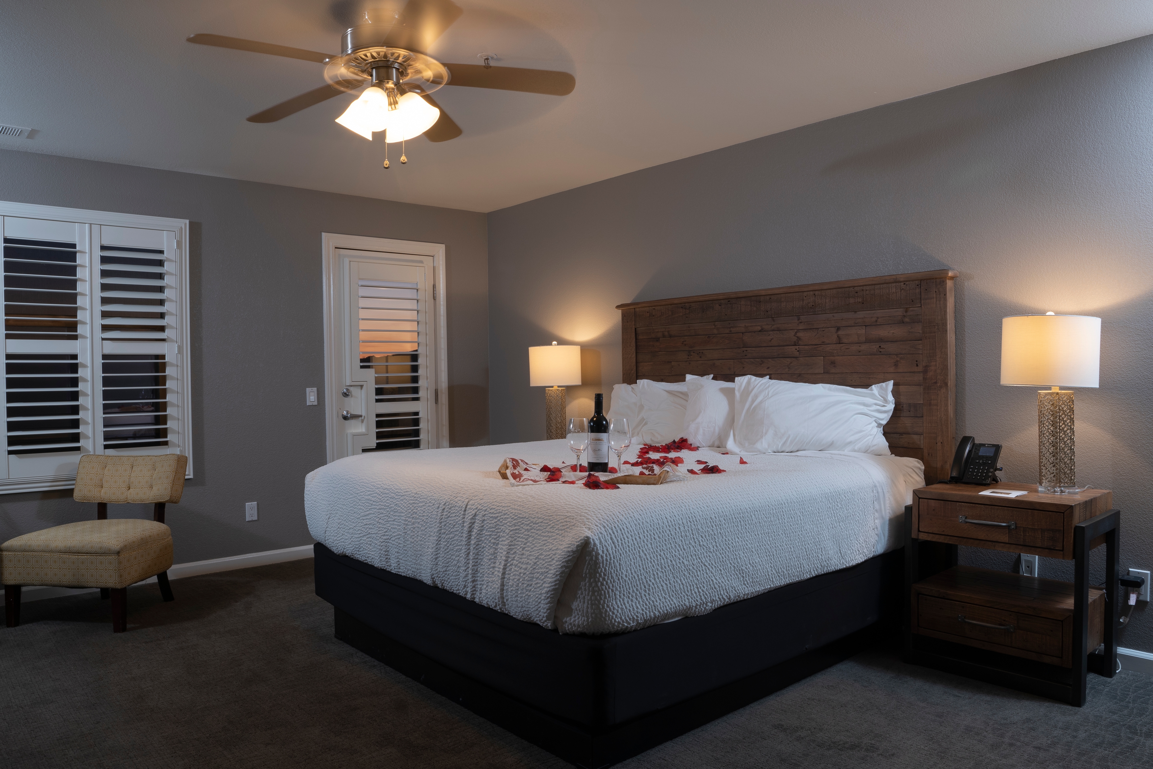 A tranquil room with a king-size bed and rose petals along the bed.