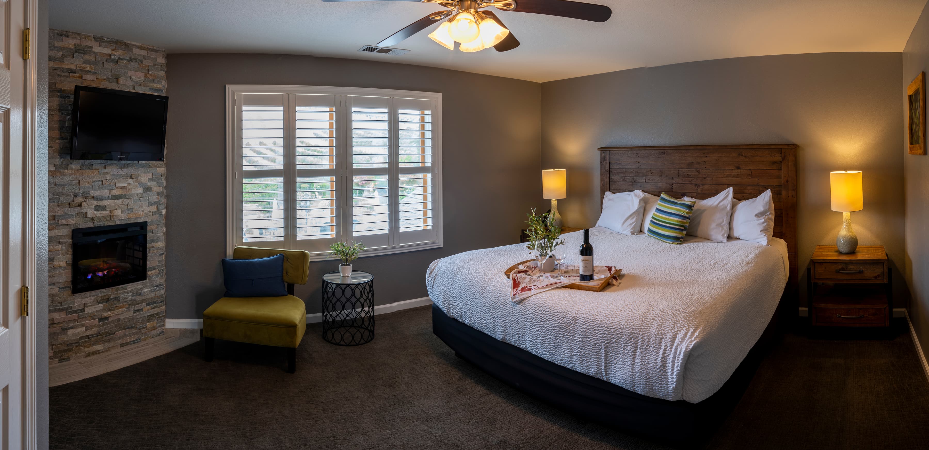 A spacious room with a king-size bed dressed in crisp white bedding, a fireplace, and a seating area with a chair and table.