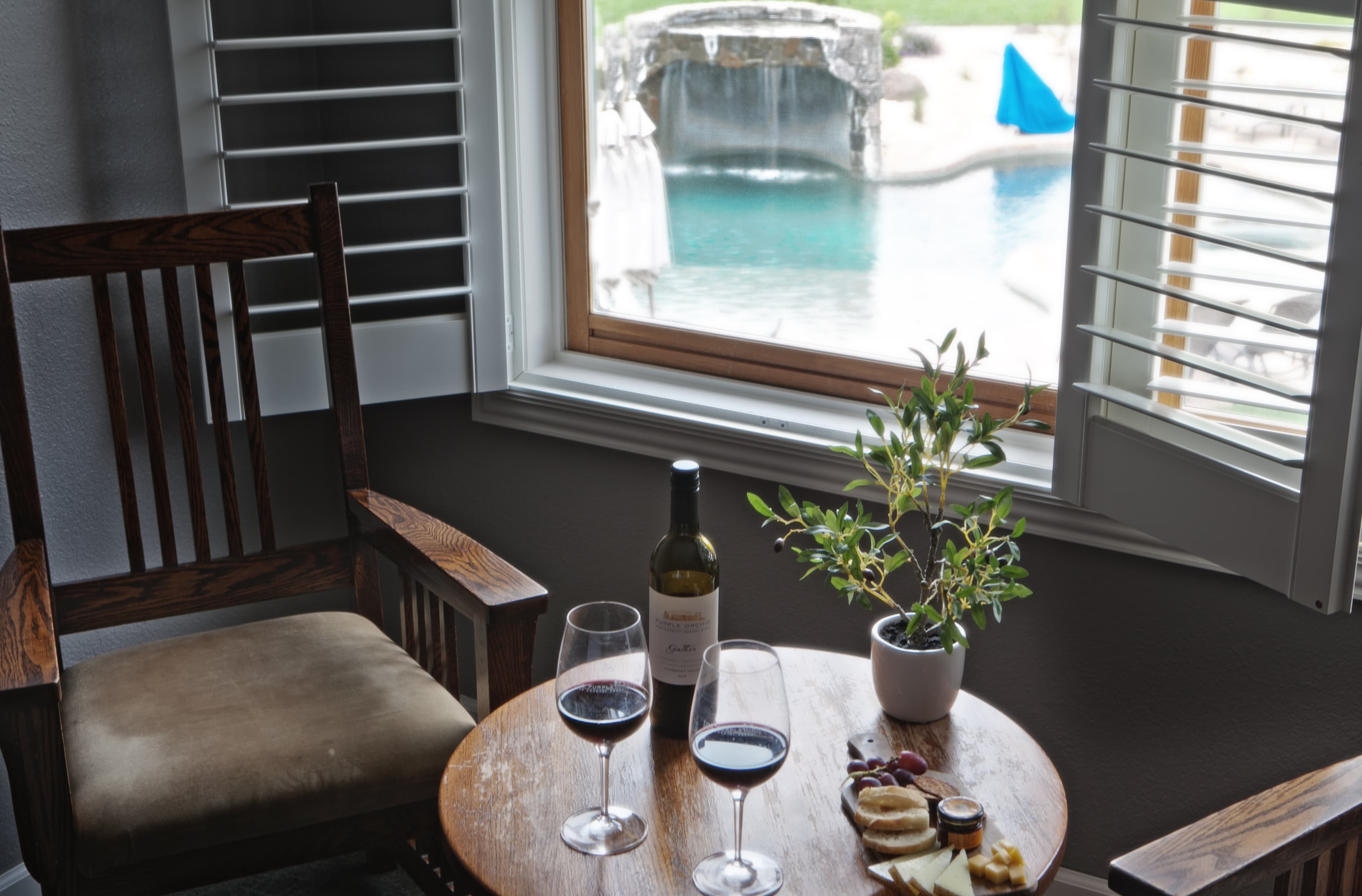 View of table with wine looking out at the pool