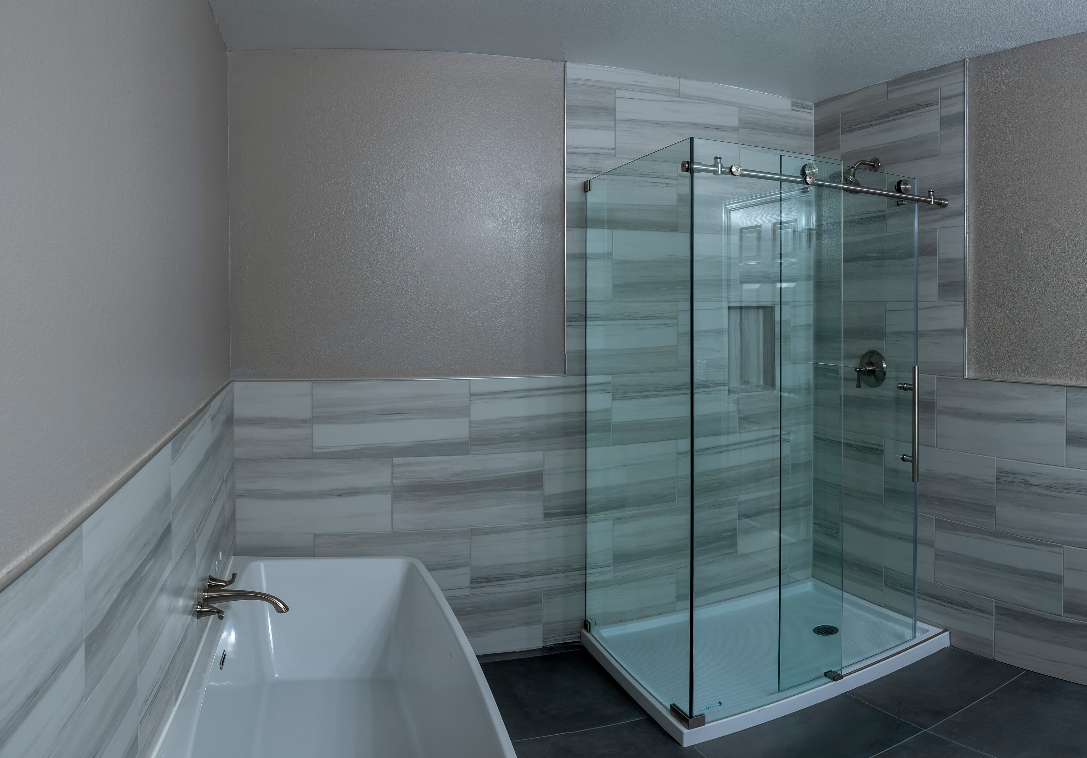 A luxurious bathroom featuring a walk-in shower with a glass door and a Bain Ultra Therapeutic Light Soaking Tub. The walls are tiled with a neutral color scheme.