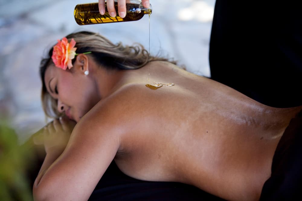 A woman receives a massage with oil while lying on her stomach.