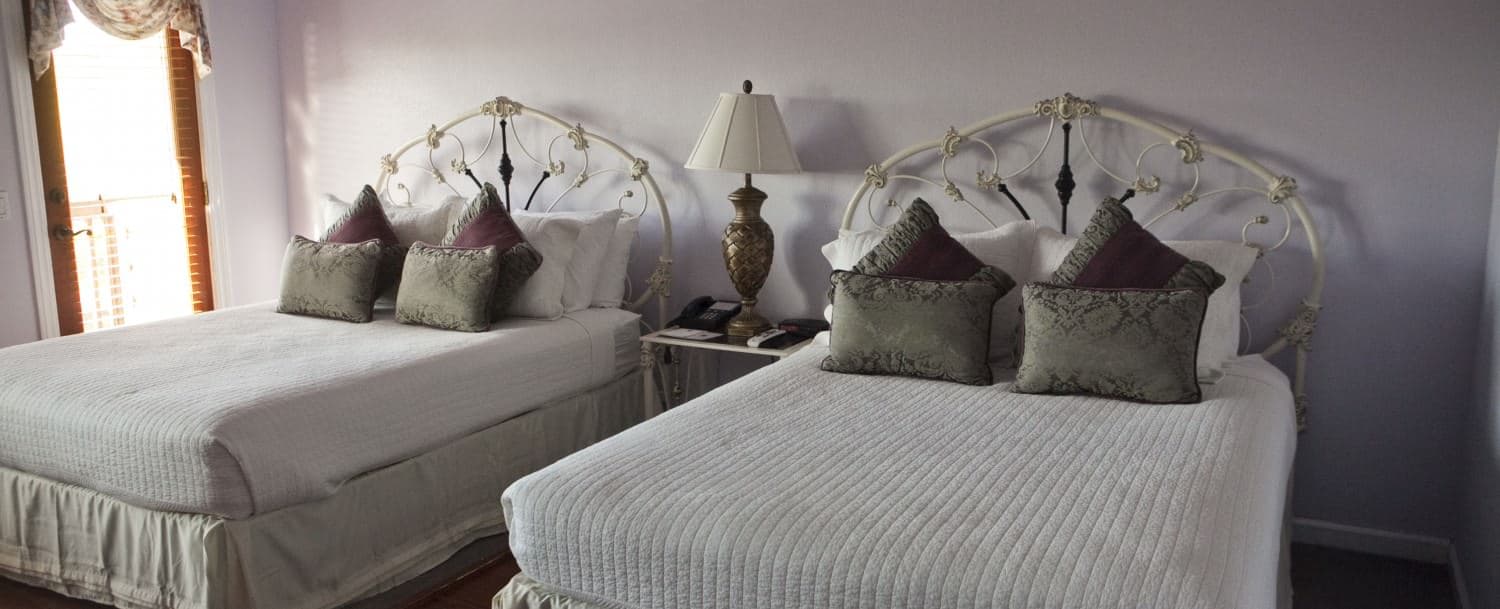 A cozy guest room with two beds, each adorned with decorative pillows and a bedside lamp.