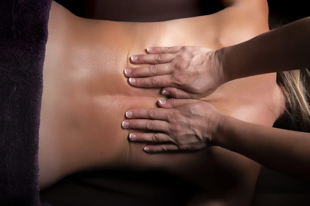 A person receiving a back massage with hands positioned on their back.