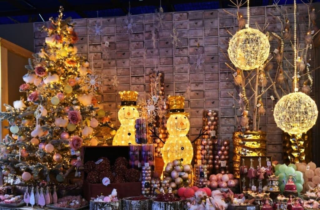 A festive display featuring a decorated Christmas tree, illuminated snowmen, and various holiday decorations and treats.
