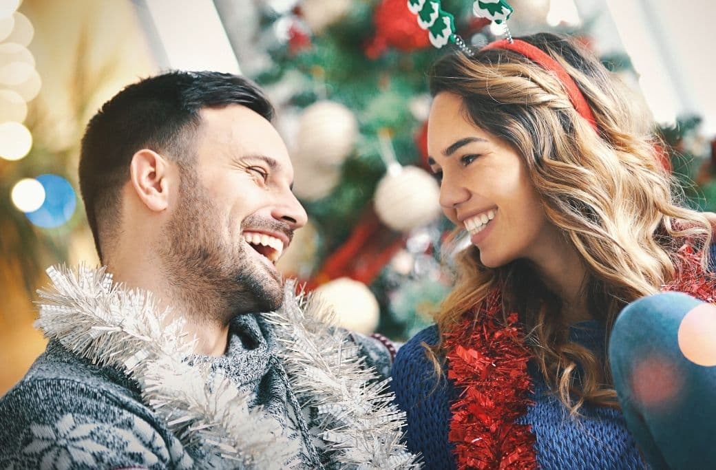 A couple joyfully sharing a moment while decorated for the holidays, with a festive background. A couple joyfully sharing a moment while decorated for the holidays, with a festive background.