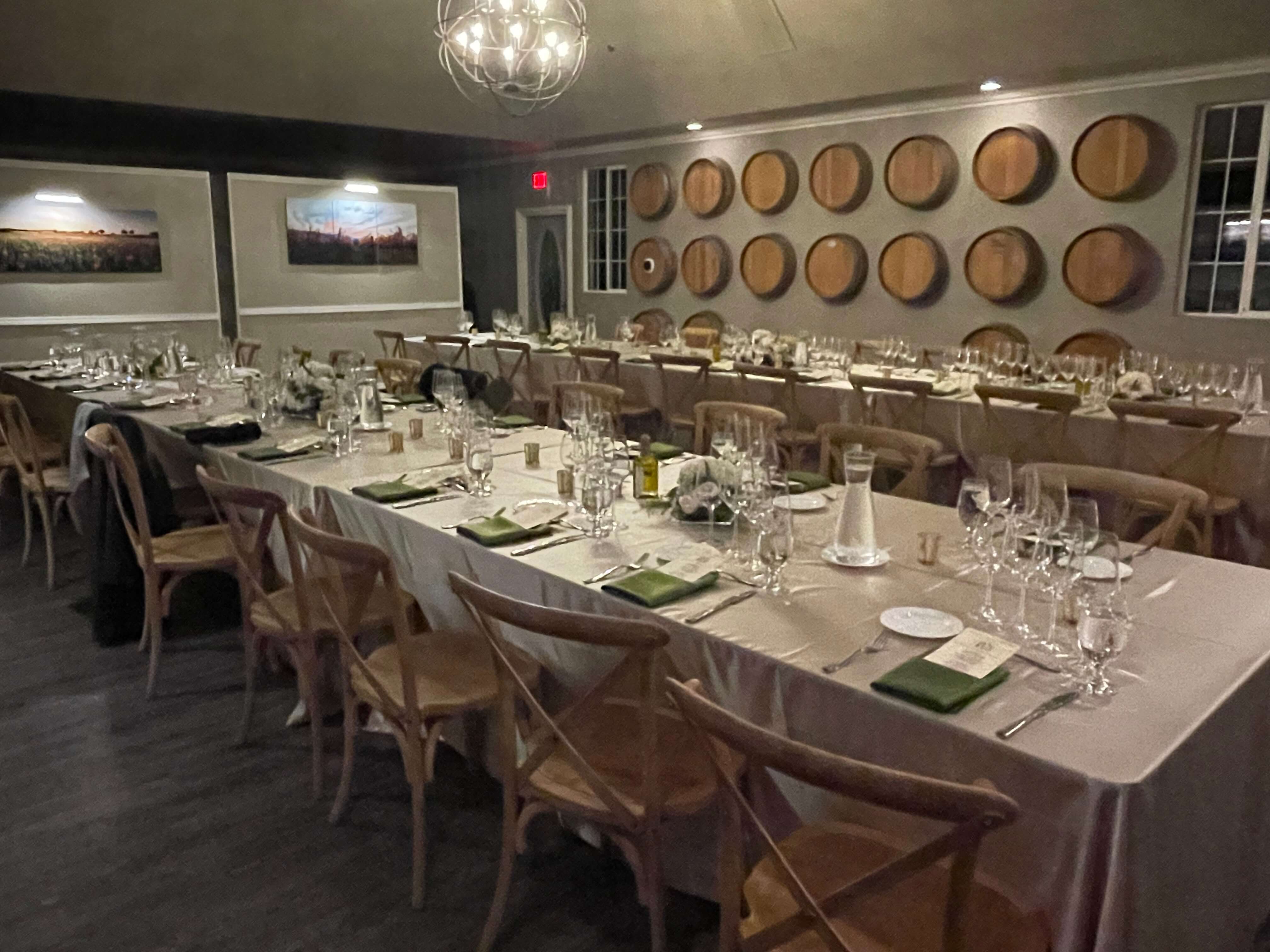 A elegantly set dining table in a warmly lit restaurant, featuring wooden barrel decor on the walls.