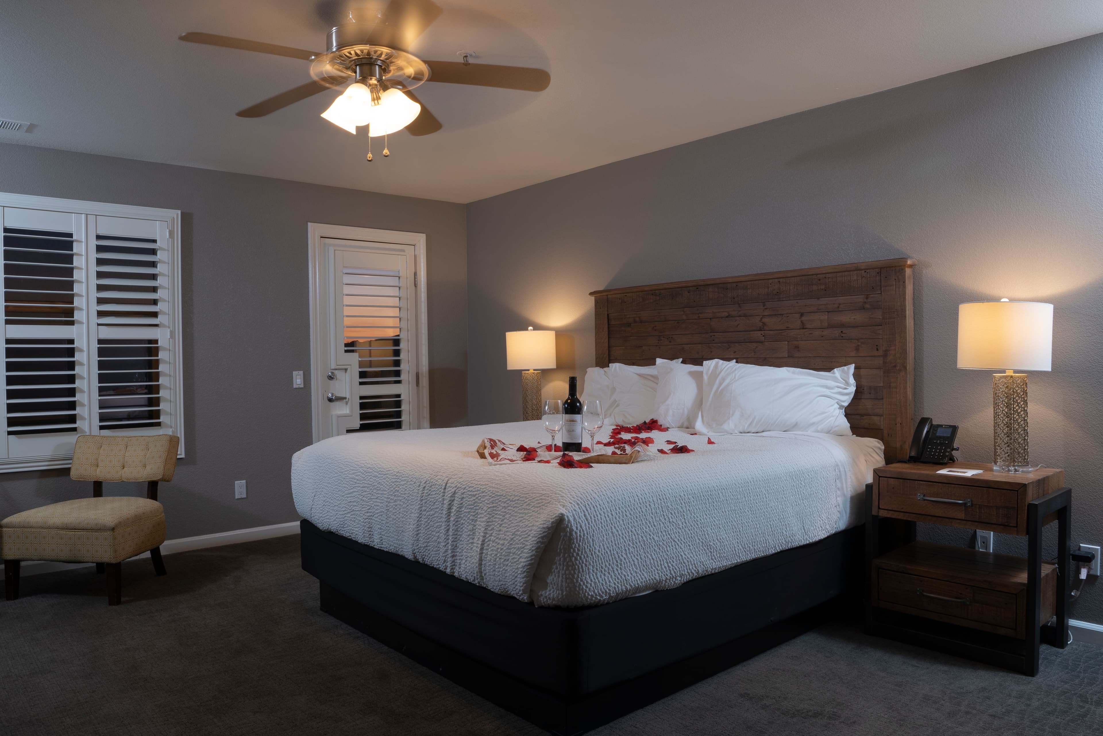 A tranquil room with a king-size bed and rose petals along the bed.