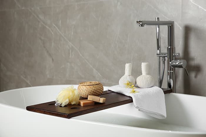 A serene bathtub with a wooden tray holding bath essentials, including sponges and wrapped soaps. A serene bathtub with a wooden tray holding bath essentials, including sponges and wrapped soaps.