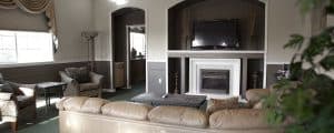A cozy living room with a light-colored sofa, modern fireplace, and a television mounted on the wall.