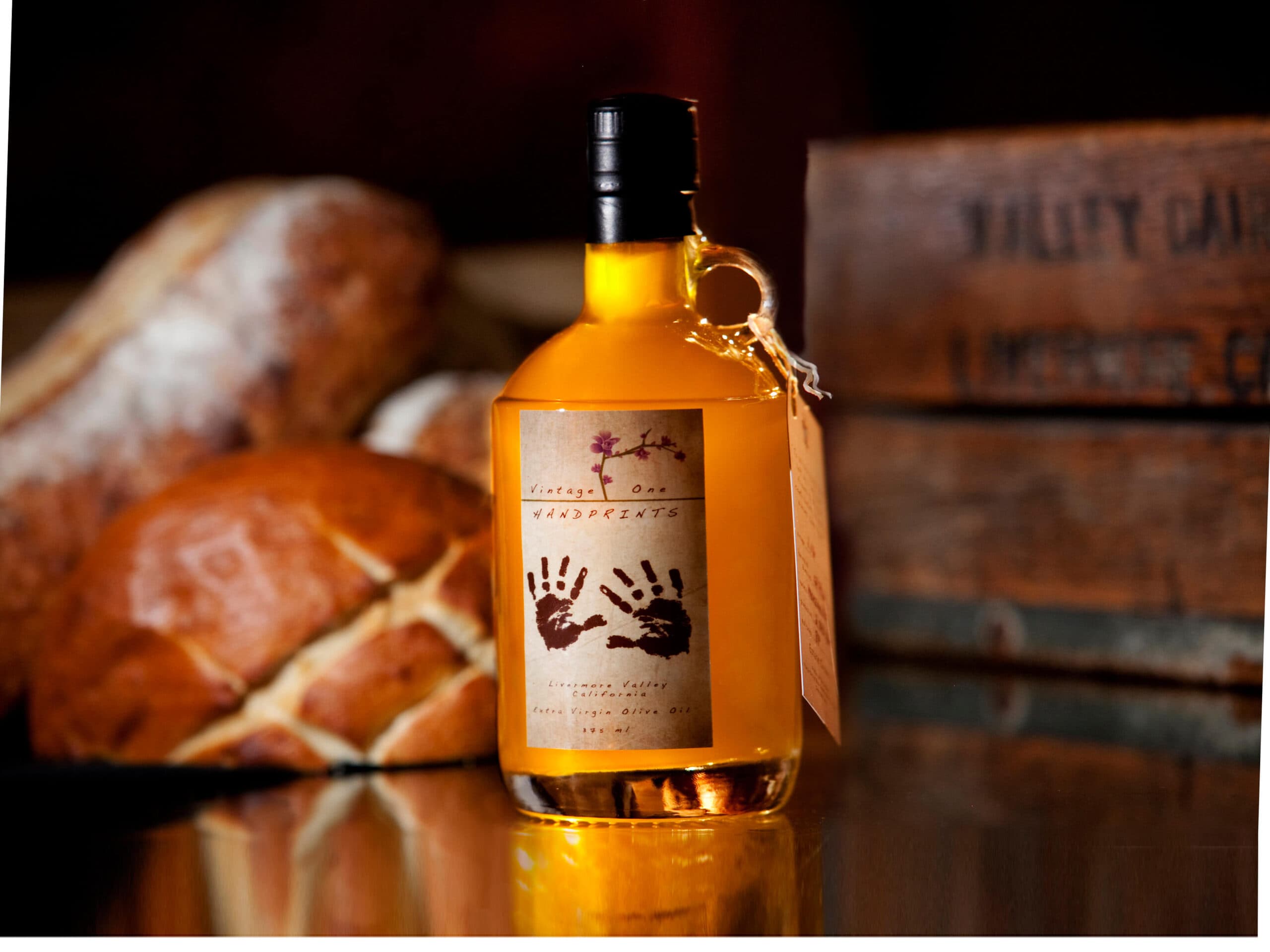 A bottle of vintage liquor with a handprint label stands in front of loaves of bread.